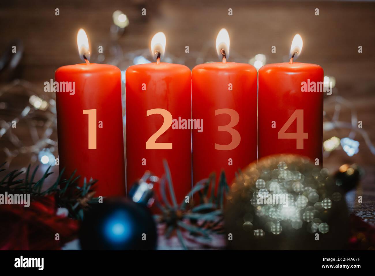 Vier nummerierte rote Adventskerzen mit zwei Kerzen angezündet und als Vorlage im Schnee liegende Weihnachtsdekoration Stockfoto