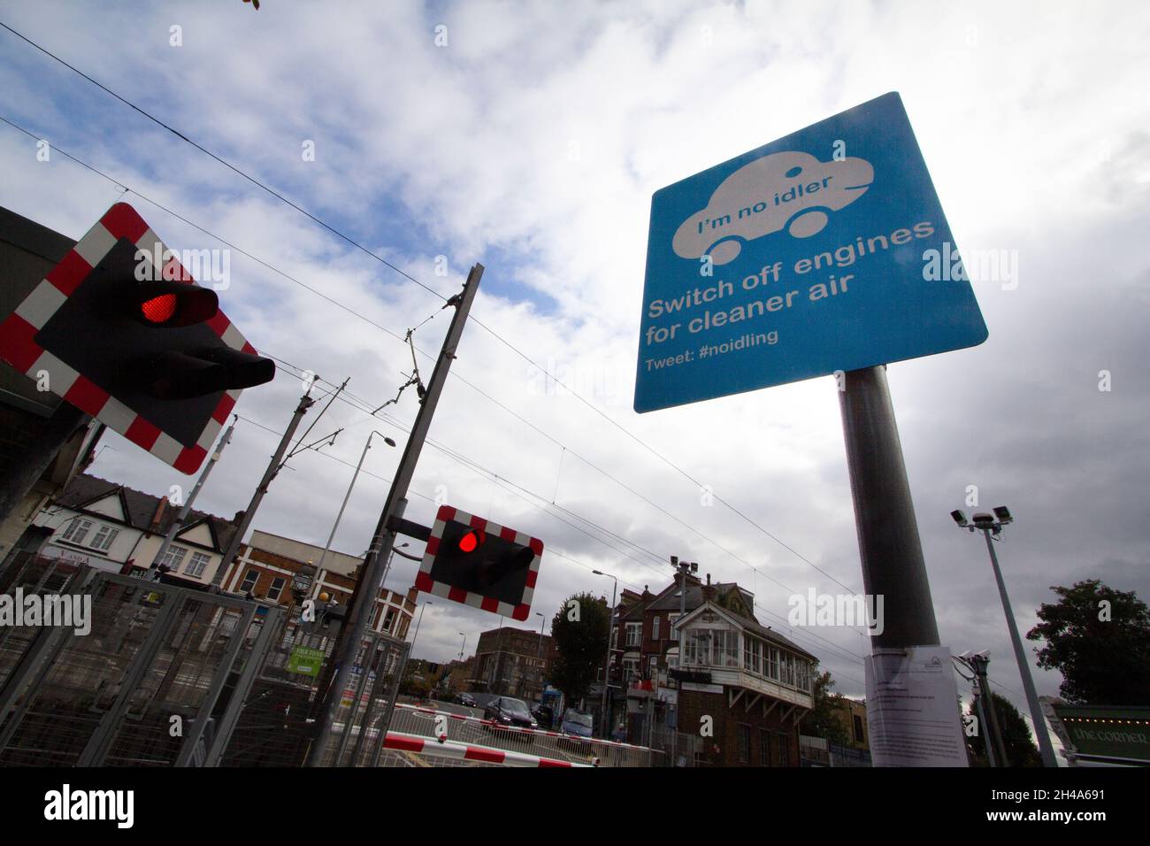 Schalten Sie die Motoren aus, damit die Luft sauberer wird, am Bahnübergang in Highams Park London, Großbritannien.das Anti-Pollution-Schild wird angebracht, um das Motorlaufen zu verhindern, während Sie auf das Anheben des Tores warten Stockfoto