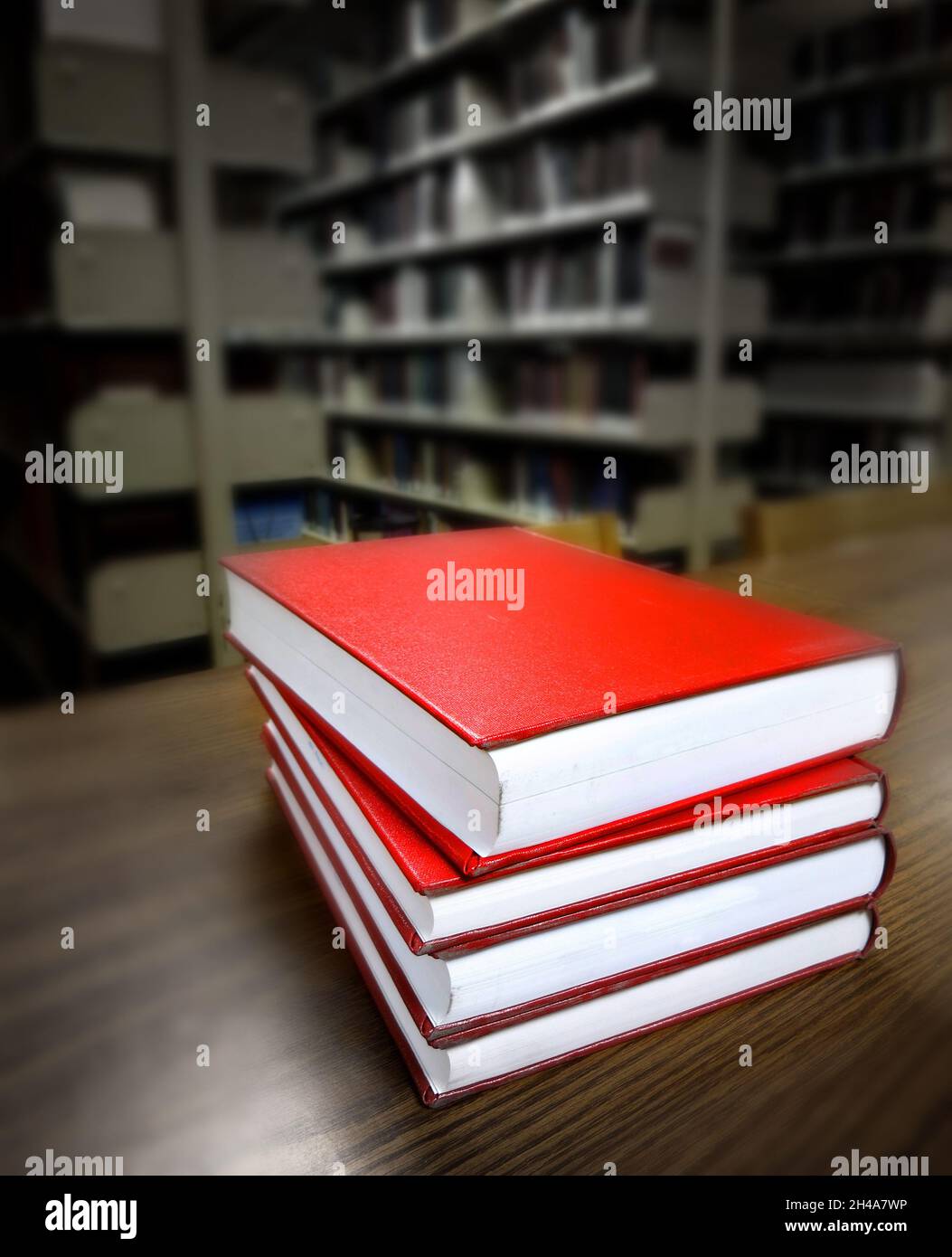 Stapel von alten roten Büchern auf einem Schreibtisch oder Tisch in einer Bibliothek zum Lernen von Bildung oder Wirtschaft Stockfoto