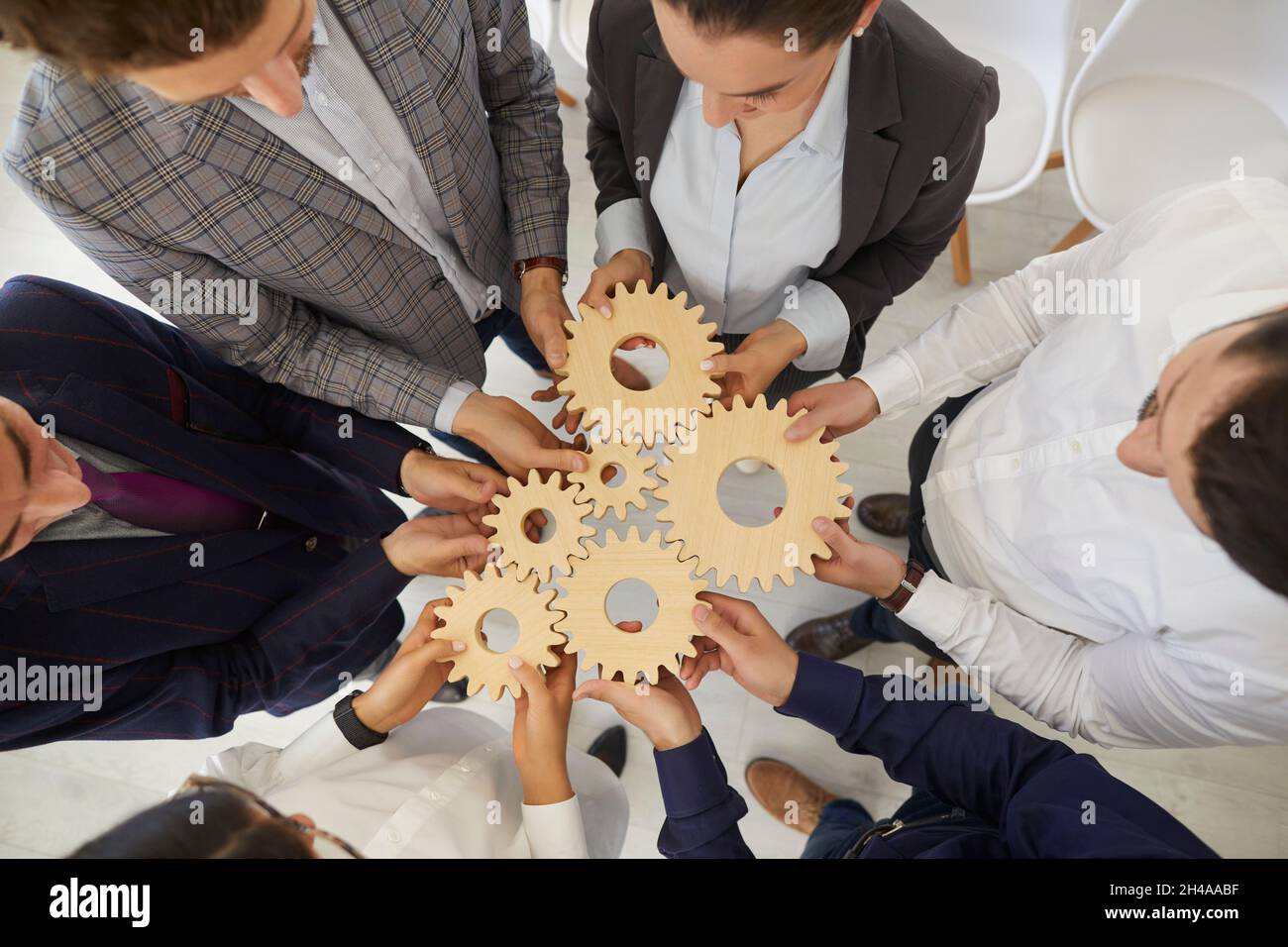 Die Kollegen in einer Ausbildung haben Holzgetriebe zusammengelegt, um zu lernen, zusammenzuarbeiten. Stockfoto