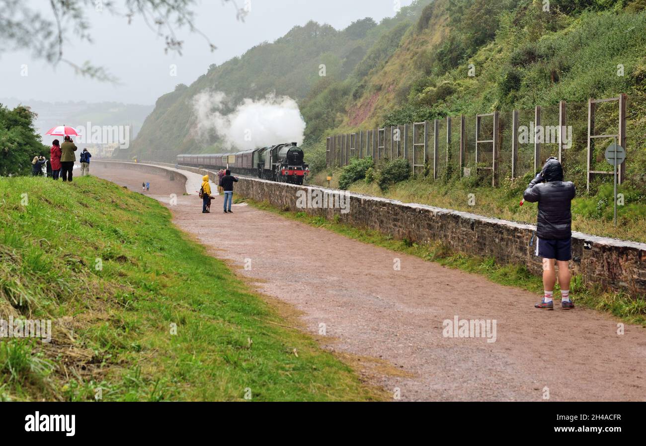 Dampfzug im Regen. Enthusiasten trotzen dem schlechten Wetter und beobachten die Mayflower-Bahntour am Sprey Point in Teignmouth, South Devon. Stockfoto