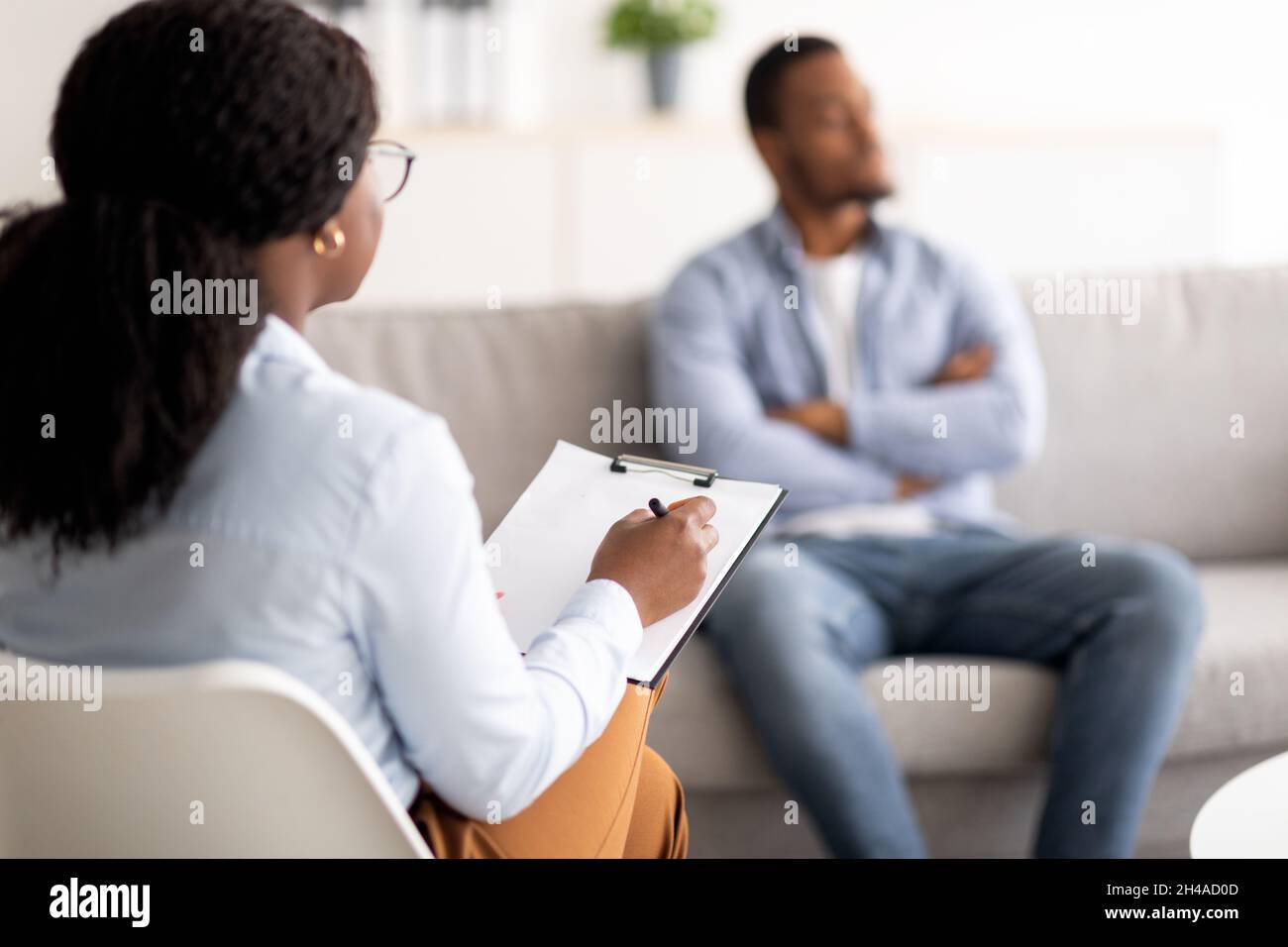 Junger schwarzer Mann mit psychischem Problem, Sitzung mit Psychotherapeut im medizinischen Büro, selektiver Fokus. Afroamerikanischer männlicher Patient, der Pr Stockfoto