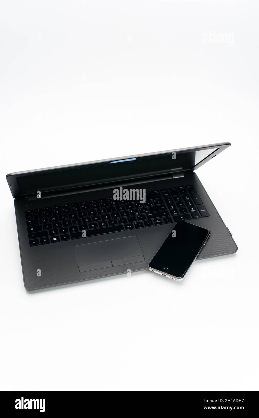 COMO, ITALIEN - 31. Okt 2021: Laptop-Computer mit geschlossenem Deckel und Smartphone auf einer weißen Arbeitsplatte mit Textraum Stockfoto