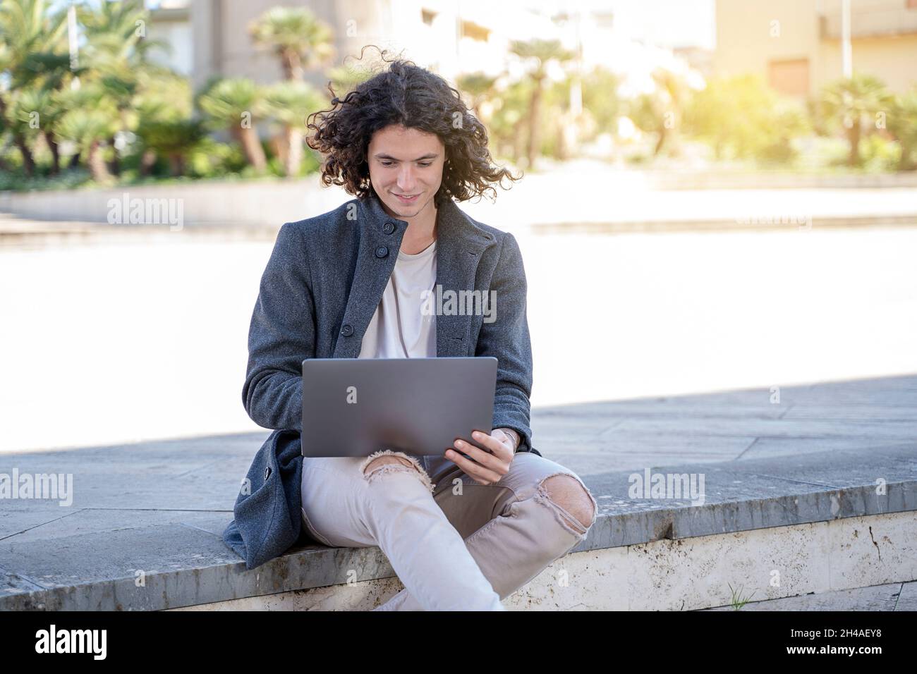 Der junge Mann arbeitet auf der Straße am Laptop Stockfoto