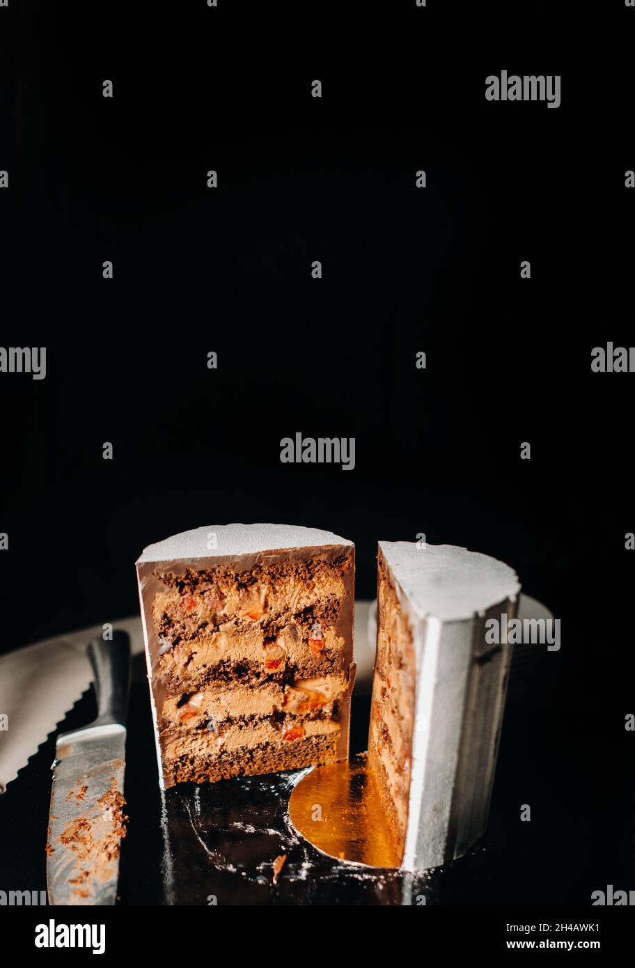 Tolle Kuchen. Geschnittener Schokoladen-Hochzeitstorte mit erstaunlicher Füllung auf schwarzem Hintergrund.großer Kuchen in weißer Schokolade. Stockfoto