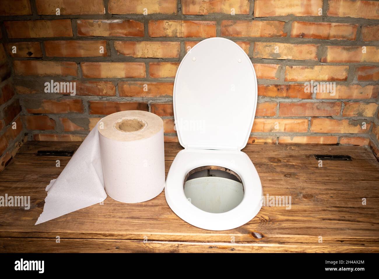 Eine einfache Dorftoilette mit einer riesigen Rolle Toilettenpapier.große Rolle Toilettenpapier in der Toilette. Stockfoto