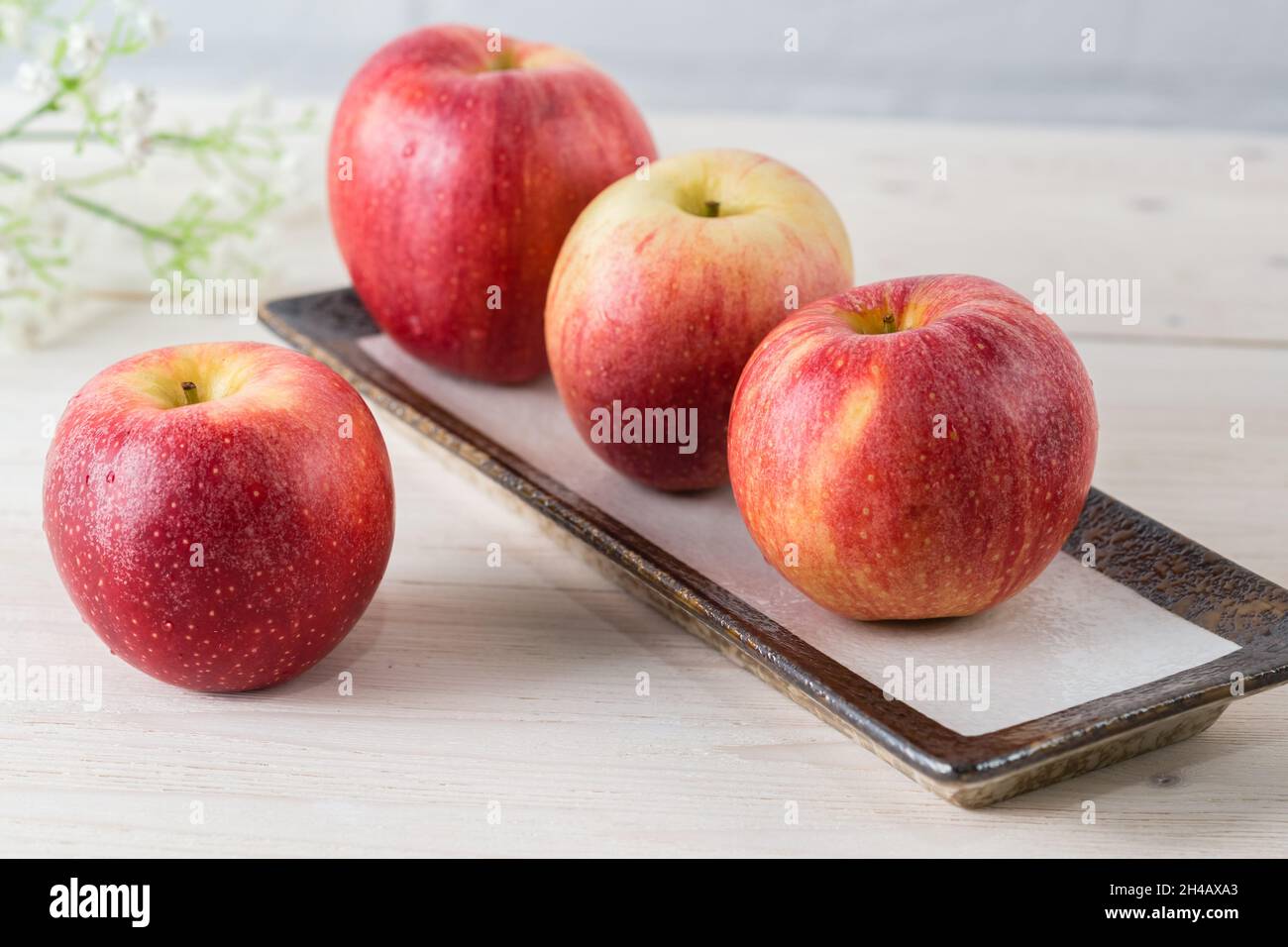 Vier saftig schöne reife rote Äpfel der frühen Wintersorte Gala auf einem weißen Holztisch Stockfoto