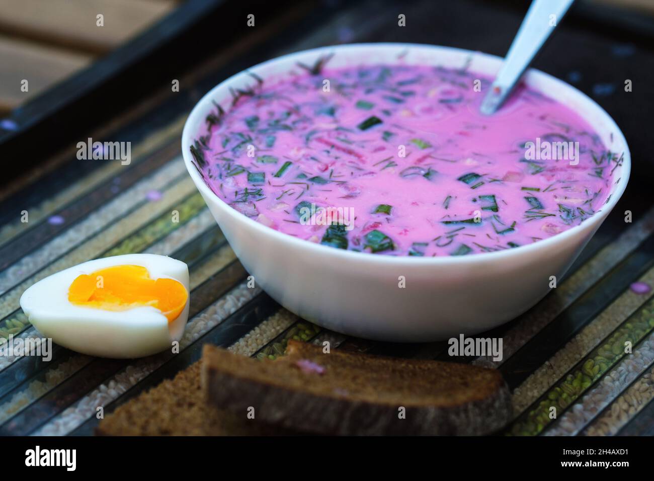 Kalte Rote Beete Suppe mit Eiern und Brot auf einer dekorativen Schale.Suppe kholodnik rot auf einer ungewöhnlichen Schale. Stockfoto