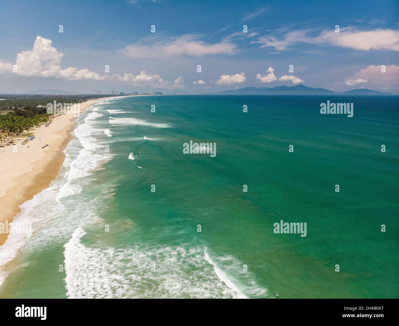 Luftaufnahme der schönen vietnamesischen Landschaft, Strand am smaragdgrünen Südchinesischen Meer in der Nähe von Hoi an unter blauem bewölktem Himmel, und entfernte Stadt Da Nang, Vietnam Stockfoto
