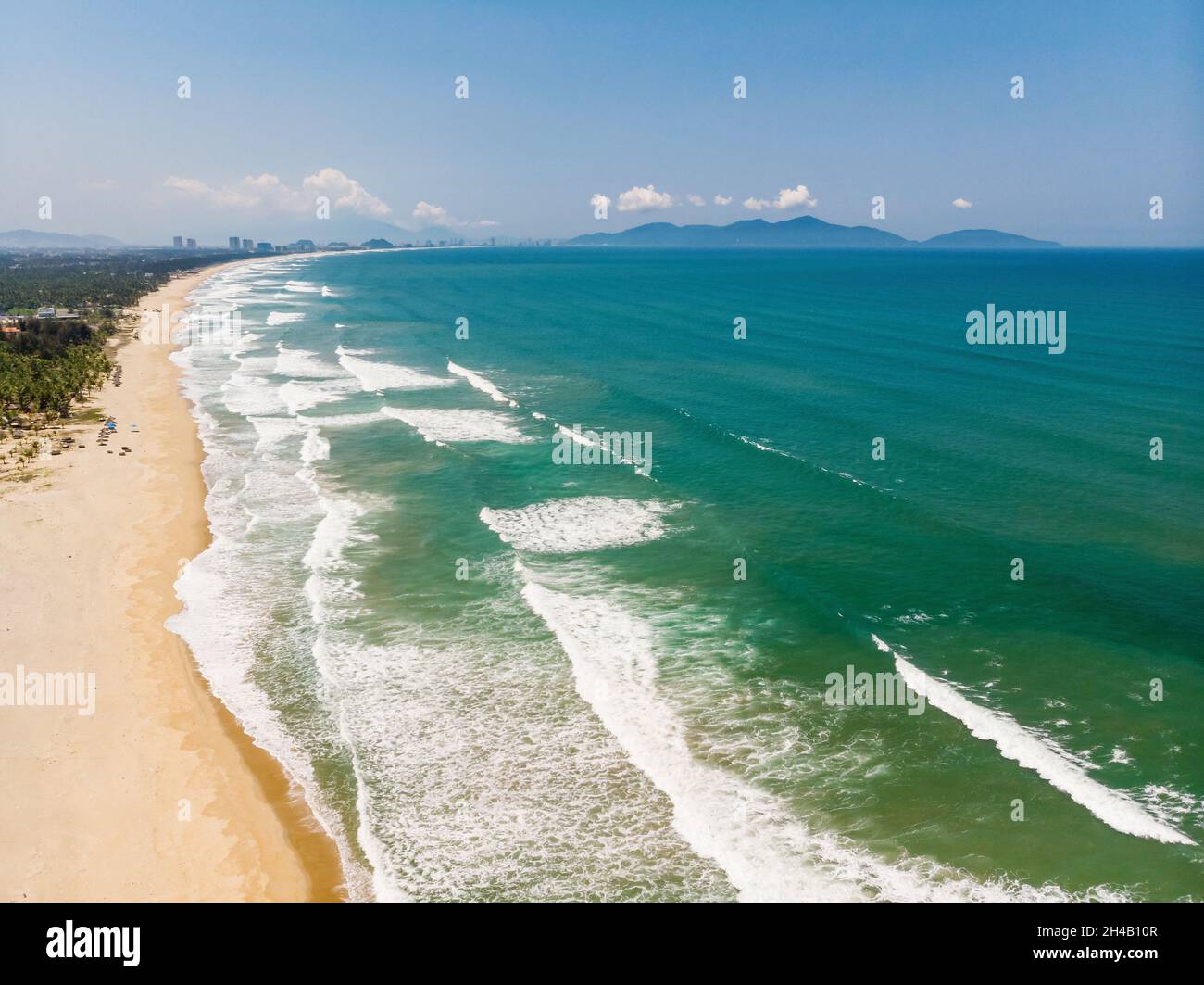 Luftaufnahme der schönen vietnamesischen Landschaft, Strand am smaragdgrünen Südchinesischen Meer in der Nähe von Hoi an unter blauem bewölktem Himmel, und entfernte Stadt Da Nang, Vietnam Stockfoto