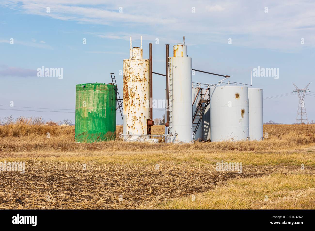 Alte Ölwannen-Lagertanks auf dem Feld der Farm. Verzicht auf Ölbrunnen, Umweltverschmutzung und Konzept der Ölförderung Stockfoto