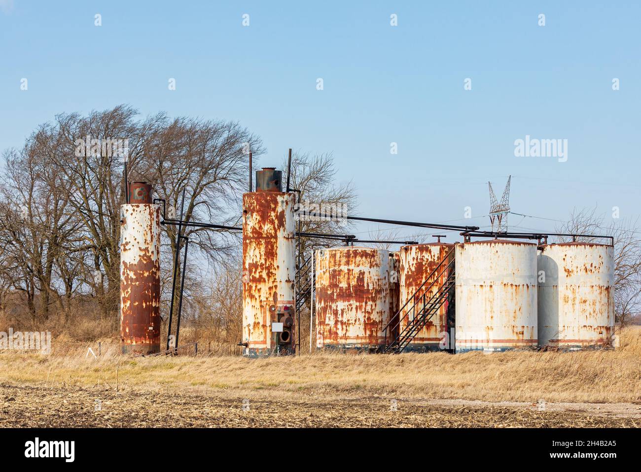 Alte Ölwannen-Lagertanks auf dem Feld der Farm. Verzicht auf Ölbrunnen, Umweltverschmutzung und Konzept der Ölförderung Stockfoto