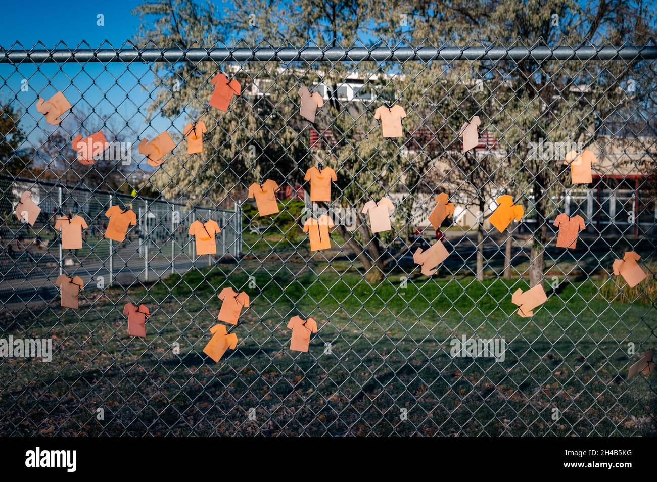 Orangefarbene Papierhemden am Zaun der indischen Wohnschule. Es wird angenommen, dass die Überreste von über 200 Kindern vor Ort in unmarkierten Gräbern begraben wurden. Stockfoto