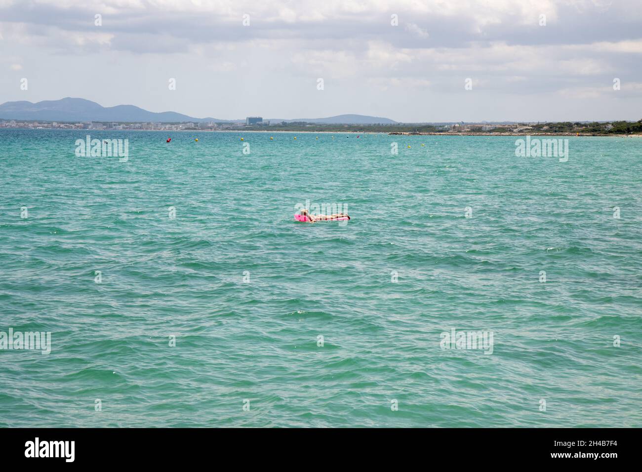 Ein Mann mittleren Alters schwimmt und legt sich auf einem aufblasbaren Pool im Meer vor der Küste von Mallorca in Spanien Stockfoto