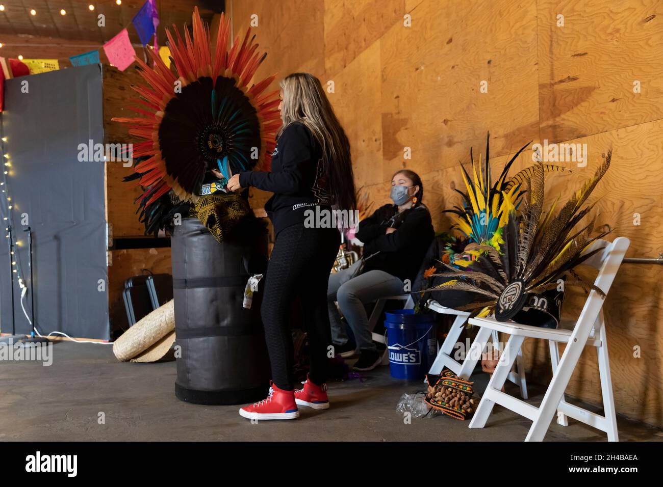 Perla Hernandez bereitet mit den aztekischen Tänzern der Huecha Omeyocan ihre Kopfbedeckung vor, bevor sie beim Dia de los Muertos Community-Feebra i auftreten wird Stockfoto