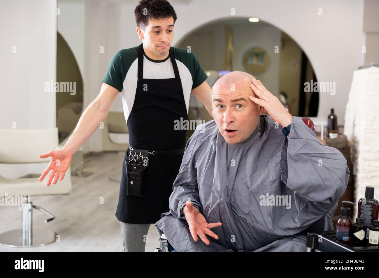 Unzufriedener Mann mit rasierten Kopf im Friseurladen Stockfoto