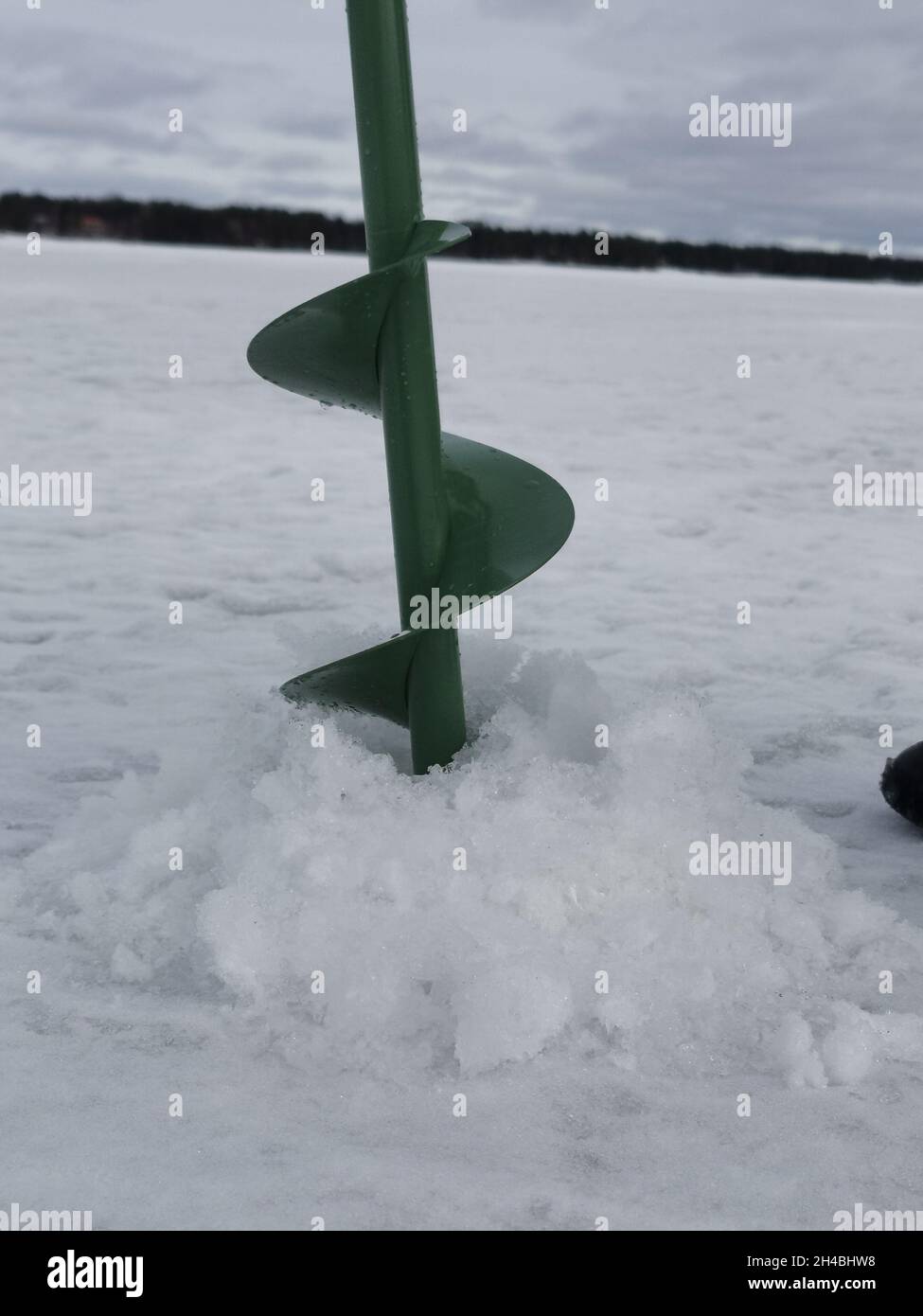 Bohren eines Lochs in das dicke Eis für den Fischfang in Finnland. Stockfoto