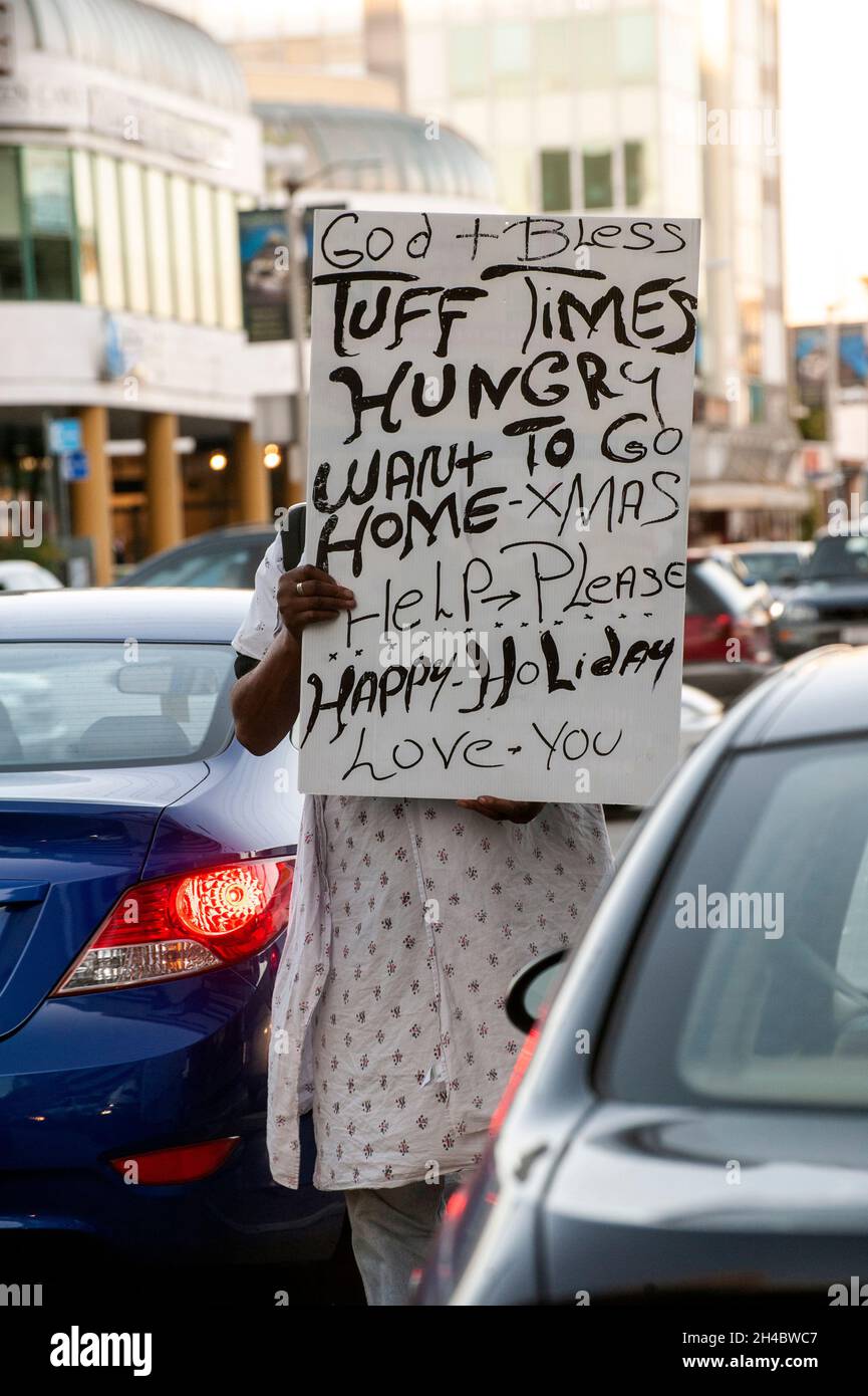 Person mit einem Schild, die mitten durch eine geschäftige Kreuzung in Beverly Hills, Kalifornien, geht Stockfoto