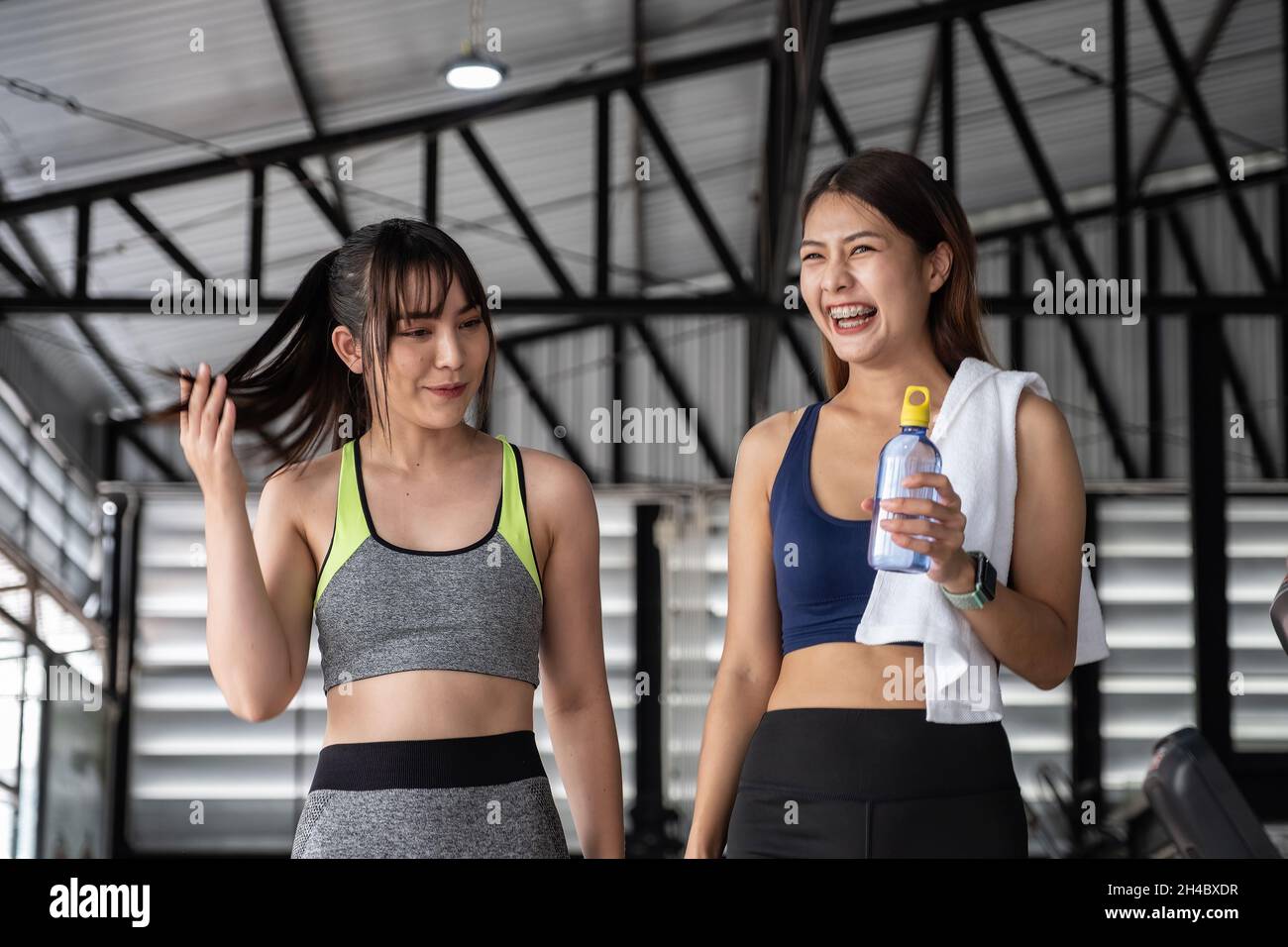 Glückliches zwei fleckiges Mädchen, das nach dem Training im Fitnessstudio miteinander redet. Stockfoto