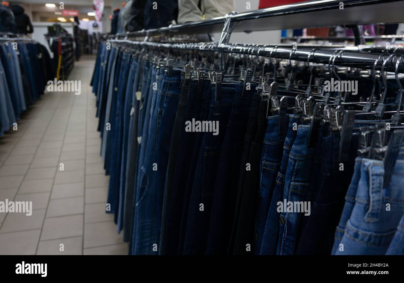 Jeans im Einkaufszentrum hängen an Kleiderbügeln. Große Auswahl an Denim-Bekleidung Stockfoto