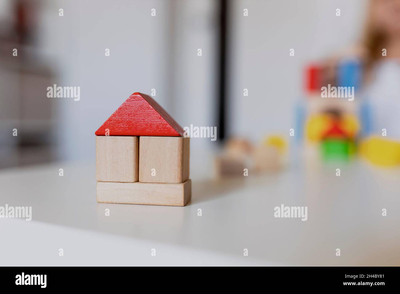 Kind Mädchen spielt mit bunten Holzspielzeug Bausteine. Kleines Kind Gebäude Turm oder Haus zu Hause oder Kinderbetreuung. Bauklotz für Baby oder zu Stockfoto
