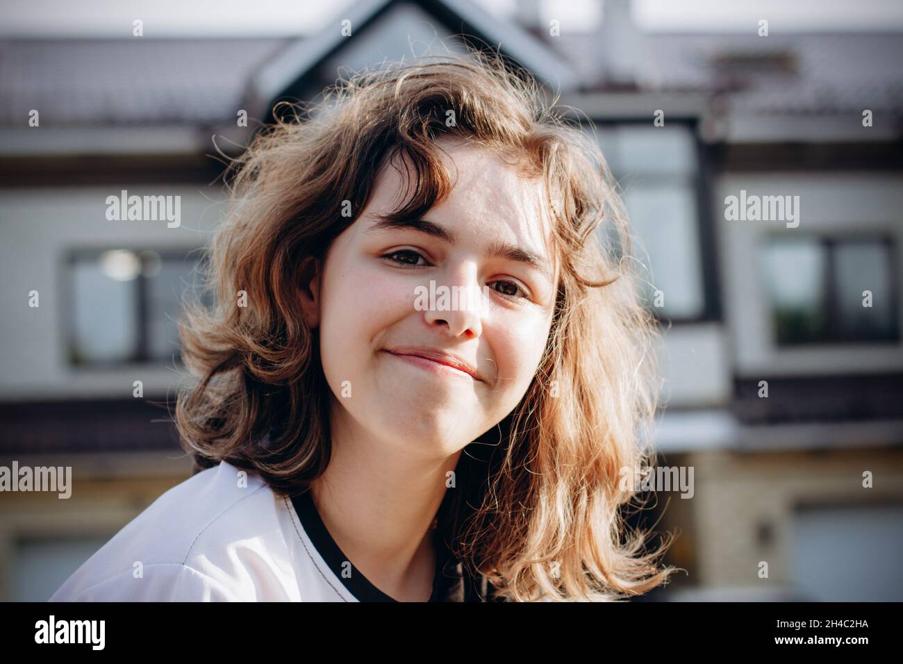 Glücklich lächelndes Teenager-Mädchen mit lockigen Haaren im Freien Stockfoto