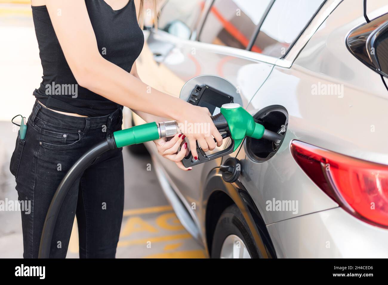 Nahaufnahme einer jungen Frau, die an einer Tankstelle Benzin in ihrem Auto bekommt Stockfoto