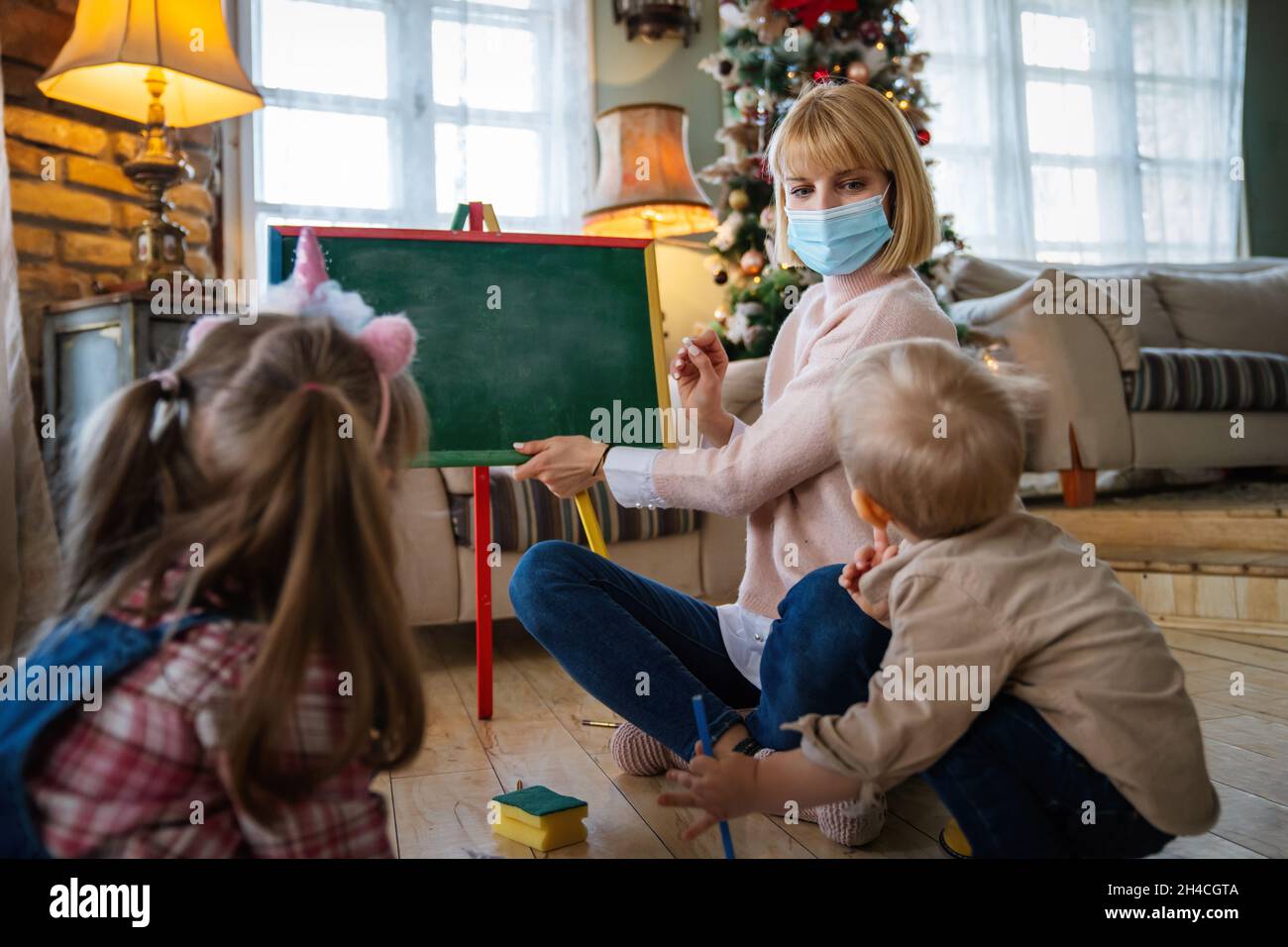 Kinderbetreterin mit Maske und Kinder, die zusammen spielen. Bildung, Coronavirus-Konzept Stockfoto