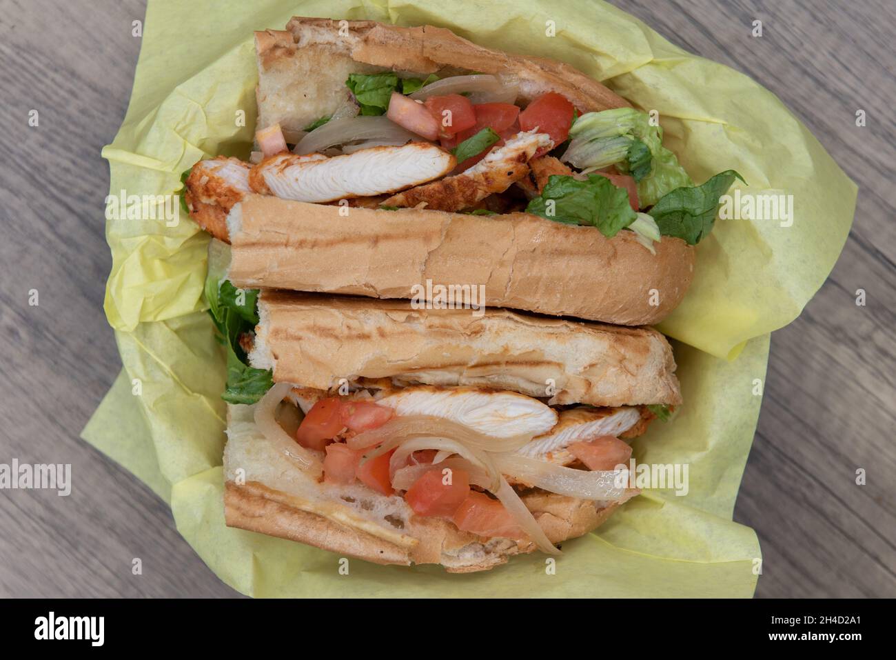 Ansicht von oben auf ein beladen Tikka Chicken Sub Sandwich voller Füllungen in einem frisch gebackenen Brötchen. Stockfoto