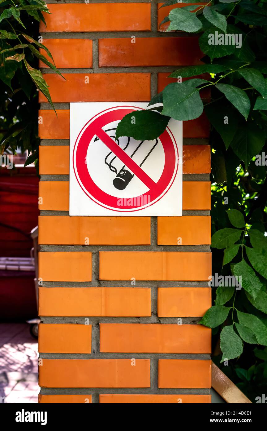 Rauchverbot an einer Ziegelmauer an einem öffentlichen Ort. Konzept des Rauchverbots an öffentlichen Orten, Gefahren und sucht des Rauchens. Vertikales Foto Stockfoto