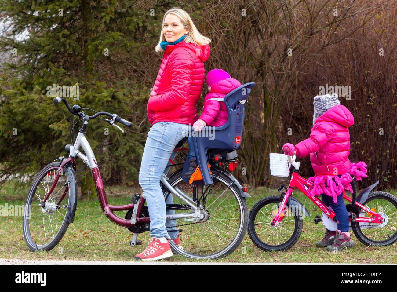 Kind im Fahrradsitz Frau auf dem Fahrrad und zwei Kinder Stockfoto