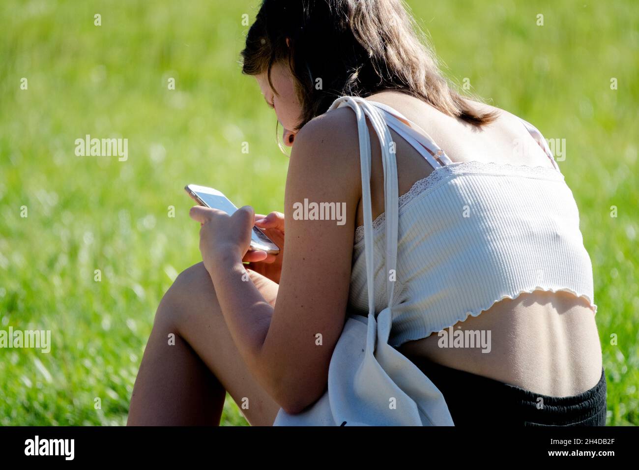 Junge Teenager Mädchen, die Telefon im Park schickt, Teenager mit Handy draußen, Smartphone Junge Teenager Generation Z Teenager Stockfoto