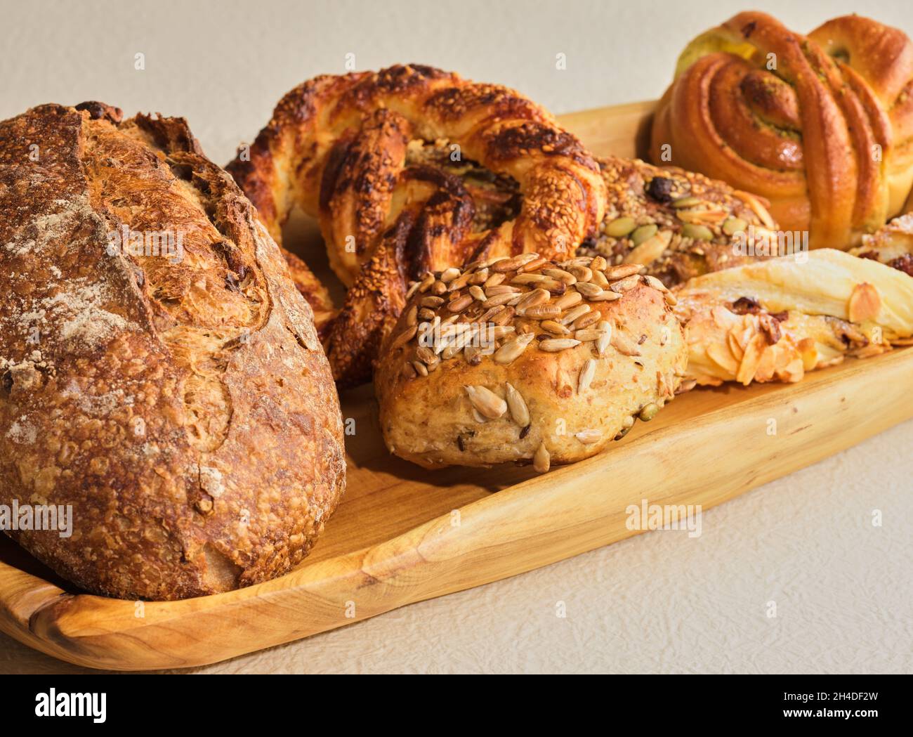 Brot auf einem Holztablett mit beigefarbenem Hintergrund Stockfoto