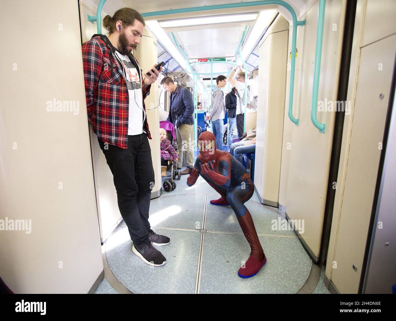 Ein Cosplayer, gekleidet als Spiderman, im DLR-Zug zur MCM London Comic Con in London Excel am Sonntag, den 25. Oktober. Stockfoto