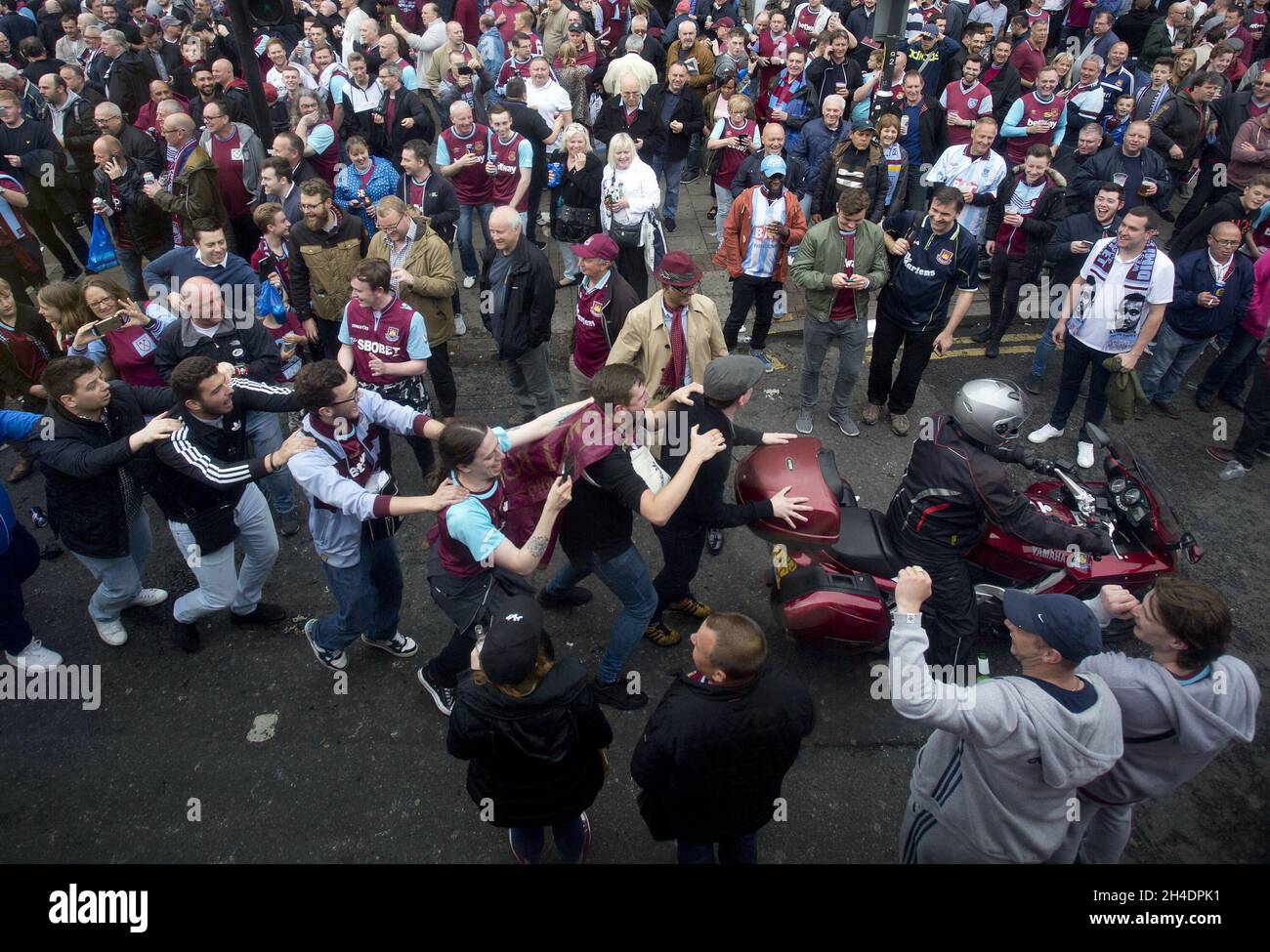 Fans von West Ham United machen ein Conga mit einem Motorradfahrer, während sie die Barking Road vor dem Boleyn Ground im Osten Londons blockieren, bevor die Hammers das letzte Spiel der Barclays Premier League im Upton Park spielten, bevor sie ins Olympiastadion ziehen. Stockfoto