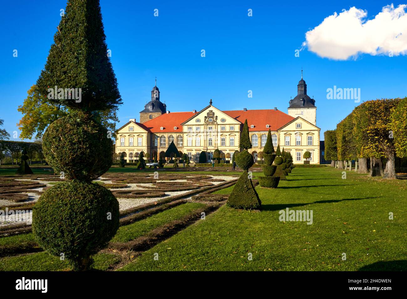 Halberstadt, 28. Oktober 2021: Blick über kunstvoll getrimmte und geschnitzte Buxenbäume in einem Barockgarten auf das Schloss Hundisburg Stockfoto