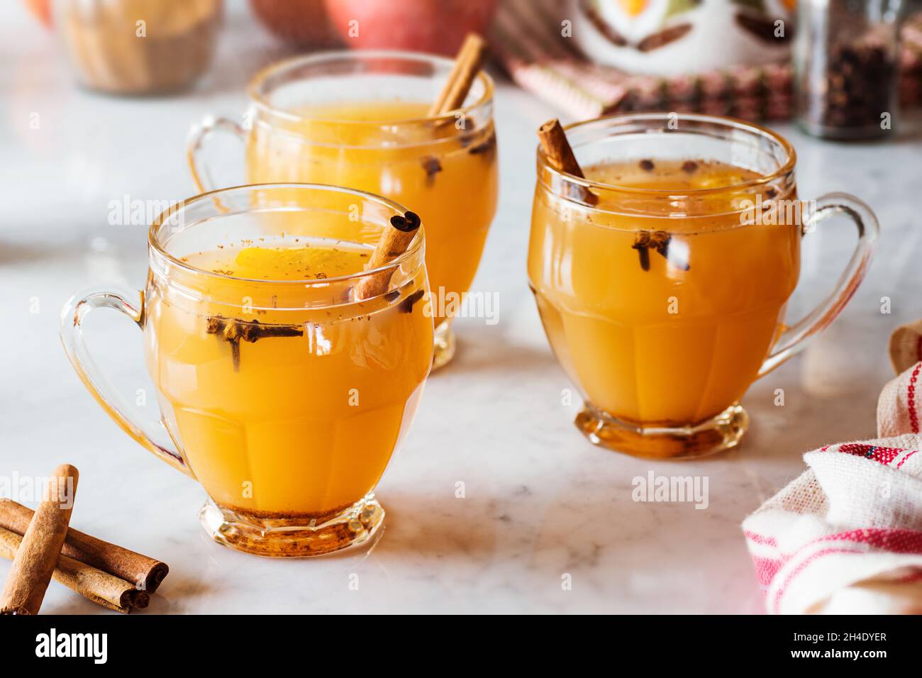 Heiß gewürzt Glühwein Apfelwein in Gläsern mit Zimt Sticks und andere Gewürze im Hintergrund auf Marmor Zähler Stockfoto