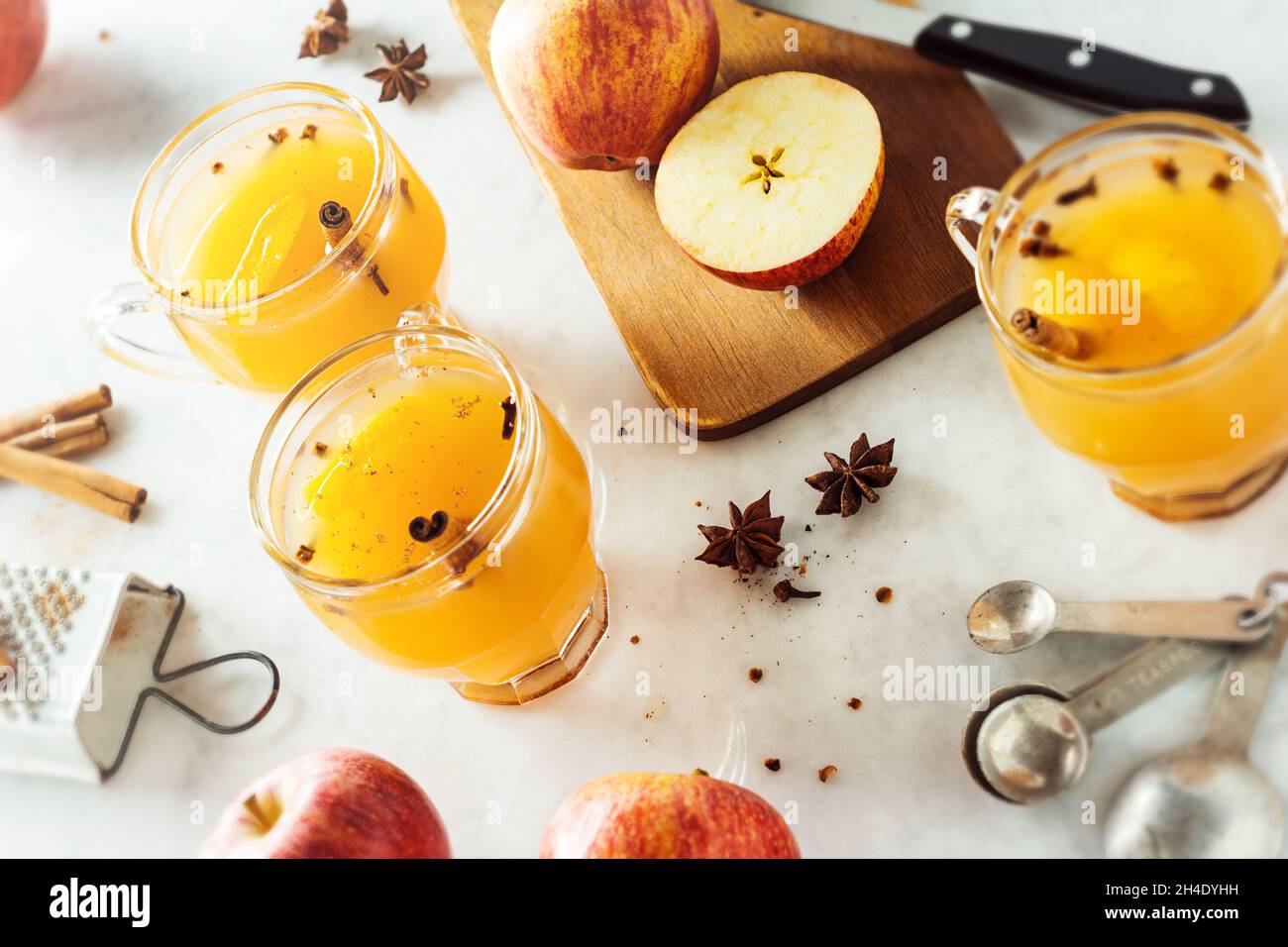 Heiß gewürzt Glühwein Apfelwein in Gläsern mit Zimt Sticks und andere Gewürze im Hintergrund auf Marmor Zähler Stockfoto