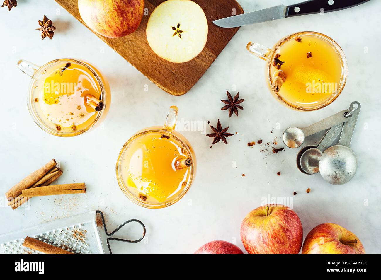 Heiß gewürzt Glühwein Apfelwein in Gläsern mit Zimt Sticks und andere Gewürze im Hintergrund auf Marmor Zähler Stockfoto