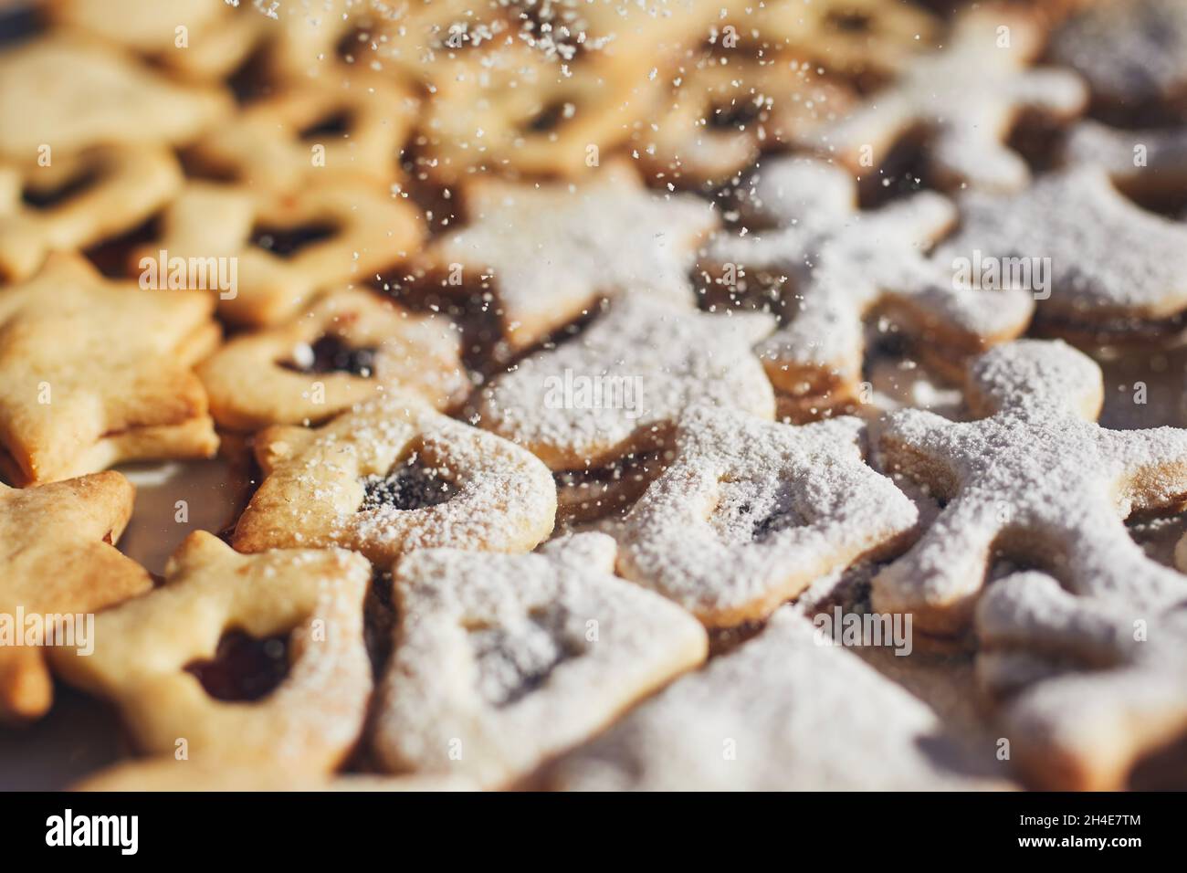 Vorbereitung von Weihnachtsbonbons im Advent. Puderzucker fällt auf Linzer Cookies. Stockfoto