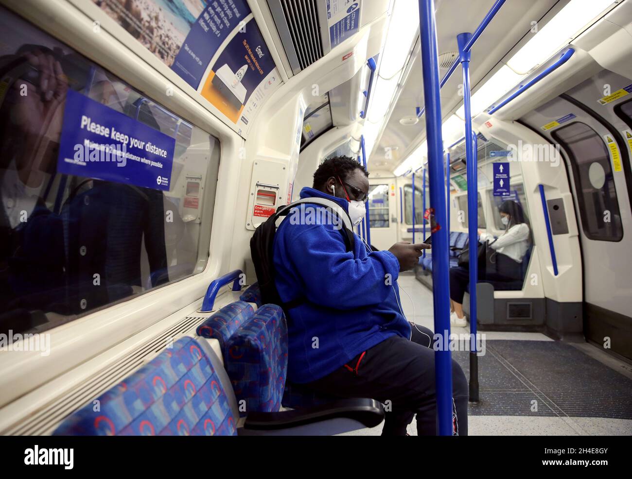 Pendler, die eine Gesichtsmaske tragen, während sie in einem U-Bahn-Zug der Piccadilly Line in London unterwegs sind, während die Regierung beginnt, einige Sperrmaßnahmen in England zu lockern. Bilddatum: Montag, 1. Juni 2020. Stockfoto