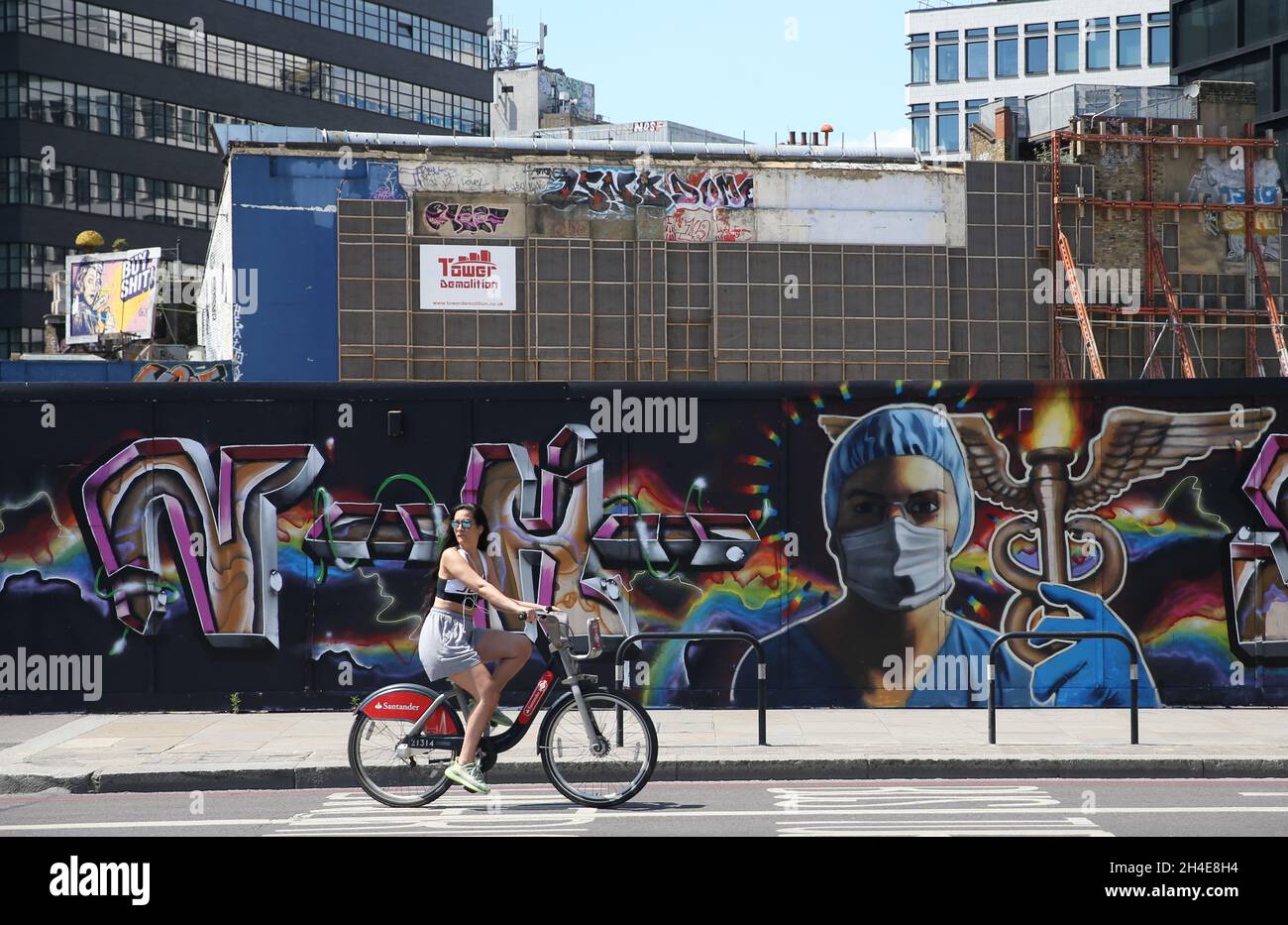 Ein Radfahrer fährt an einem Graffiti vorbei, auf dem ein Gesundheitshelfer mit voller persönlicher Schutzausrüstung in der Nähe von Shoreditch im Osten Londons abgebildet ist, während die Regierung beginnt, einige Sperrmaßnahmen in England zu lockern. Bilddatum: Montag, 1. Juni 2020. Stockfoto