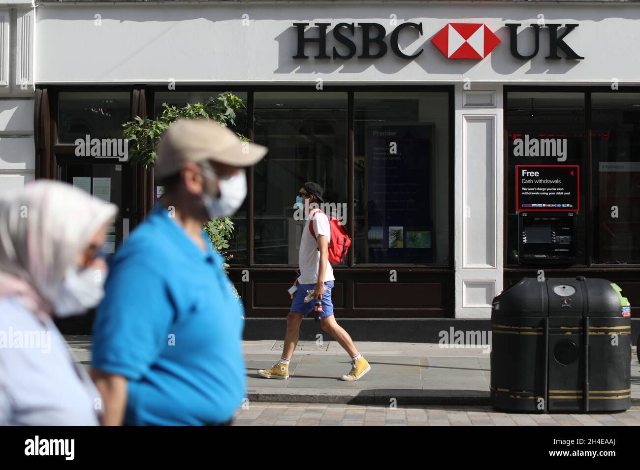 Menschen mit Gesichtsbedeckung passieren eine Niederlassung von HSBC in Großbritannien in der Nähe von Covent Garden in London, da die Bank angekündigt hat, ihre Pläne zur weltweiten Reduzierung von 35,000 Arbeitsplätzen zu beschleunigen, nachdem die Covid-19-Krise die Bank gezwungen hatte, weitere 3,8 Milliarden US-Dollar (£2,9 Milliarden US-Dollar) zur Deckung der uneinbringlichen Schulden zur Seite zu stellen. Bilddatum: Freitag, 7. August 2020. Stockfoto