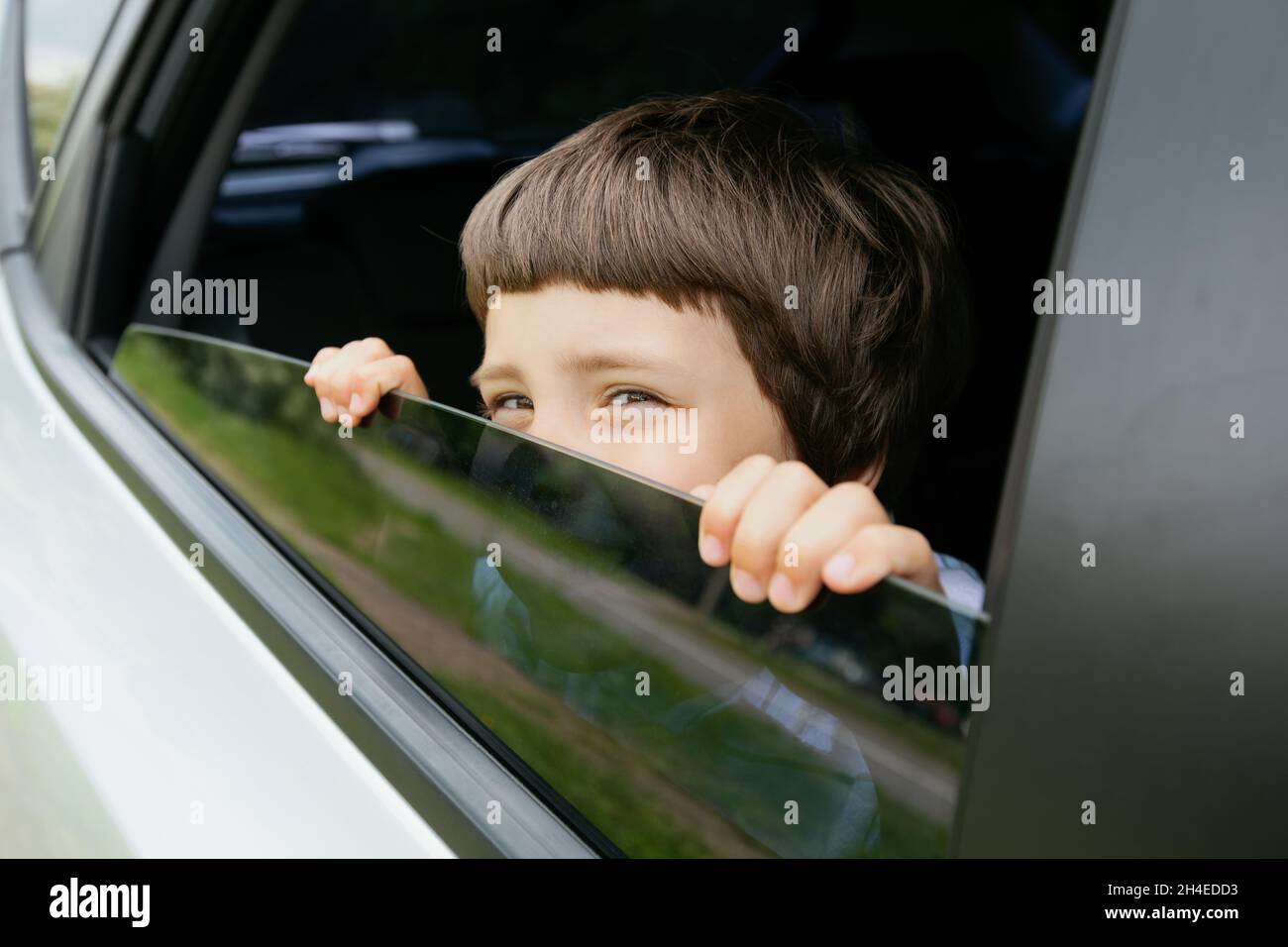 Neugieriger Kleiner Junge, Der Während Der Fahrt Aus Dem Geöffneten Autofenster Heraus Peitscht Stockfoto