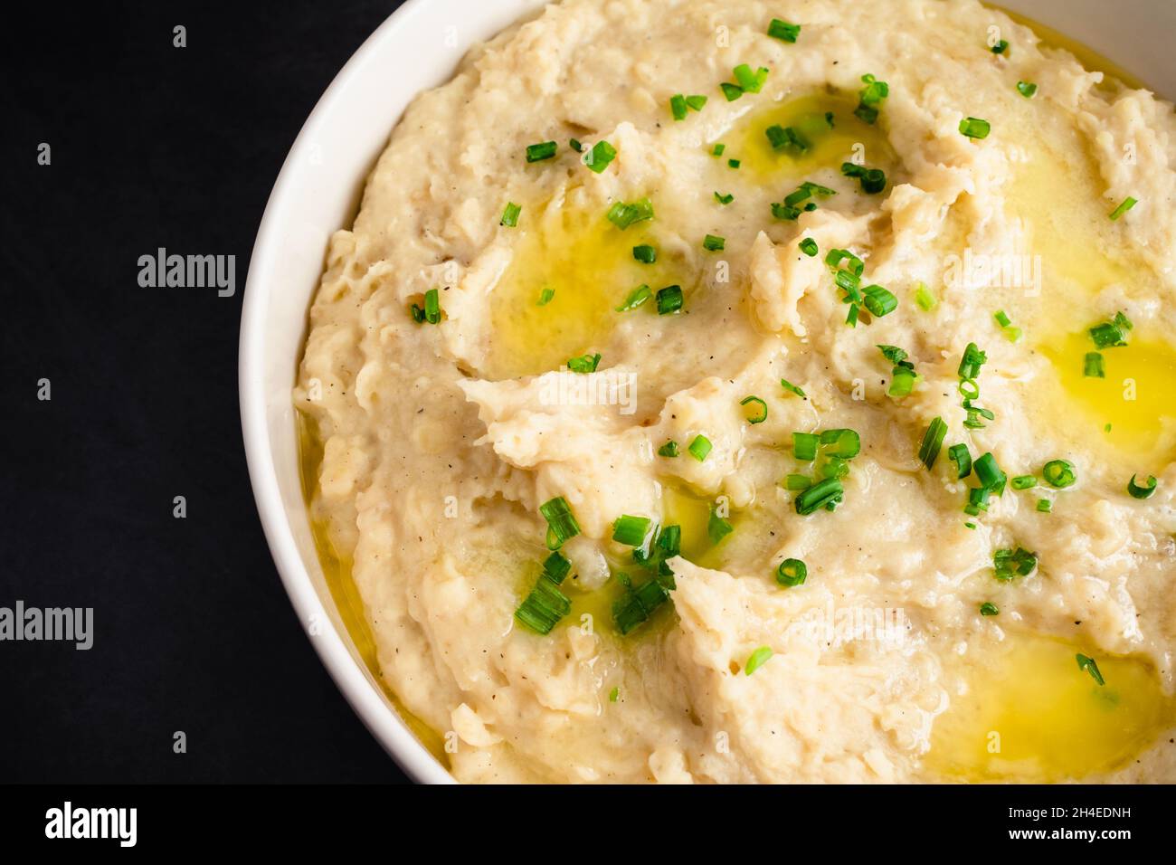 Kartoffelpüree mit Knoblauch in einer Servierschüssel: Eine große Schüssel mit geschlagenen Kartoffeln, gekrönt mit Schnittlauch und geschmolzener Butter Stockfoto