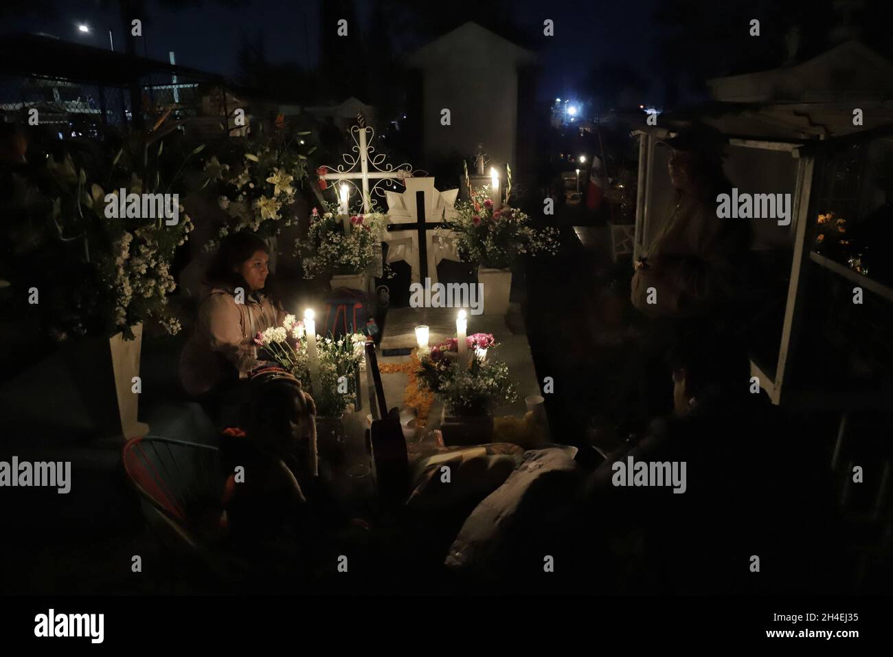 Eine Person hält einen Abend auf dem Friedhof von San Pedro Tláhuac ab, um die Ankunft ihrer verstorbenen Angehörigen zu erwarten, Verwandte schmücken Blumen, Bringen Sie ihnen Essen und singen Sie ihnen an den Gräbern als mexikanische Traditionen des Tages der Toten, um ihnen eine gute Rückkehr auf dem Weg nach Mictlan zu wünschen. Am 1. November 2021 in Mexiko-Stadt, Mexiko. (Foto von Fernanda Rojas/ Eyepix Group) Stockfoto