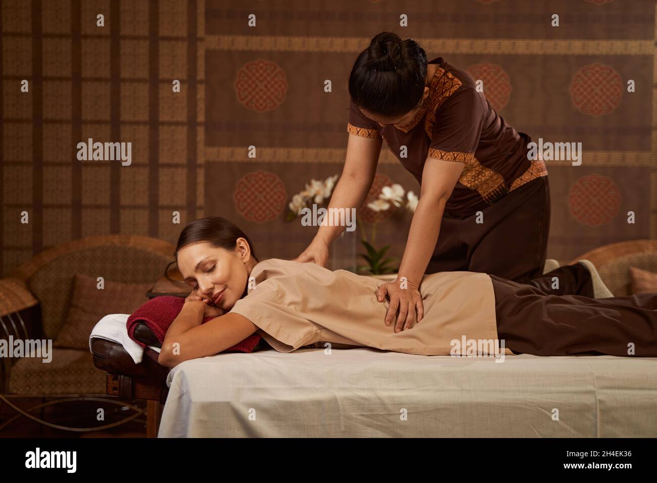 Erfahrene Massotherapeutin, die weibliche Patientin mit Thai-Massage massiert Stockfoto