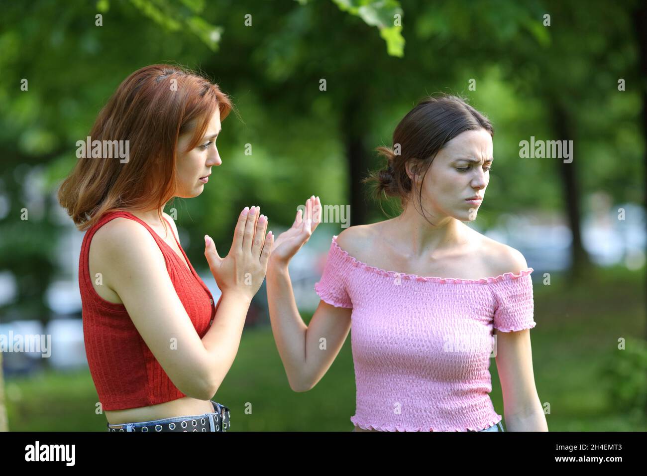 Bedauert Frau bittet ihre Freundin in einem Park um Vergebung Stockfoto