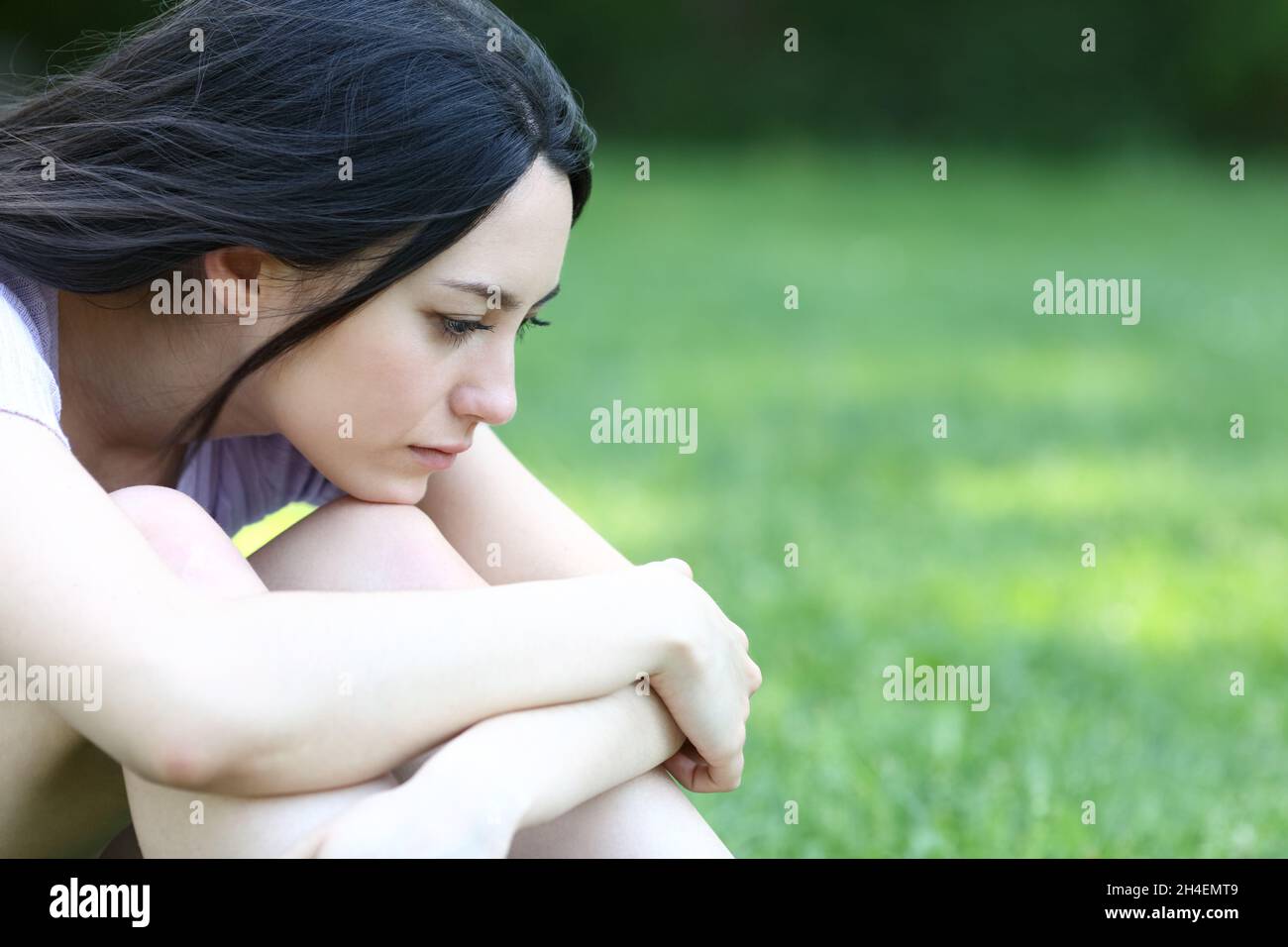 Traurige asiatische Frau, die sich alleine in einem Park beschwert Stockfoto