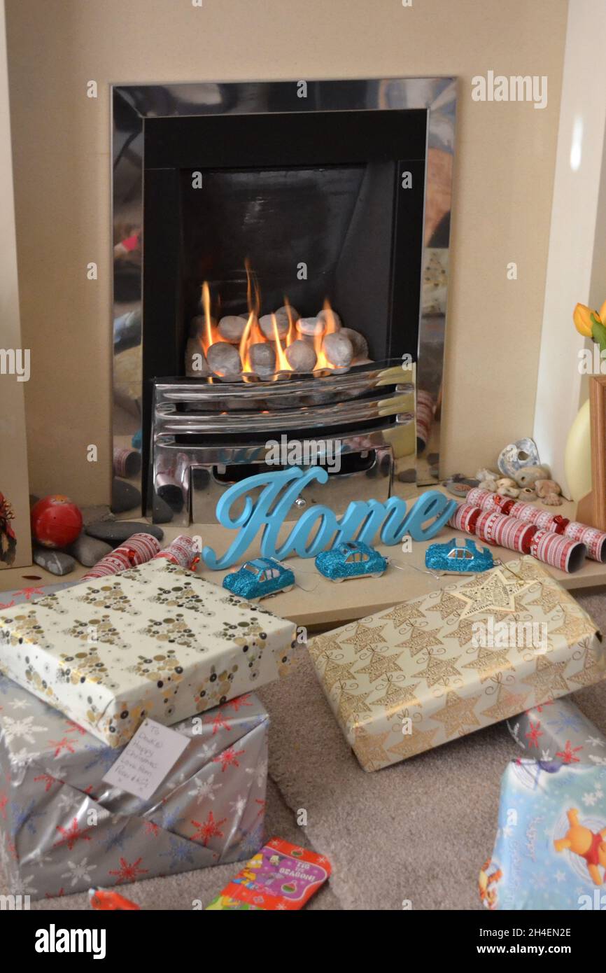 Weihnachtsgeschenke vor Einem brennenden Gasfeuer - Weihnachtsmorgen - Weihnachtstag - Festliche Feierlichkeiten - Yorkshire - UK Stockfoto